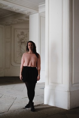 Junge Frau steht neben einer Säule auf Schloss Solitude 