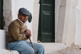 Alter Mann in Portugal sitzt vor einem Hauseingang 