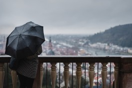 Frau mit Regenschirm schaut über Heidelberg 