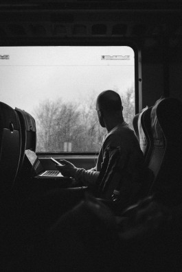 Mann schaut im Zug aus dem verregneten Fenster 